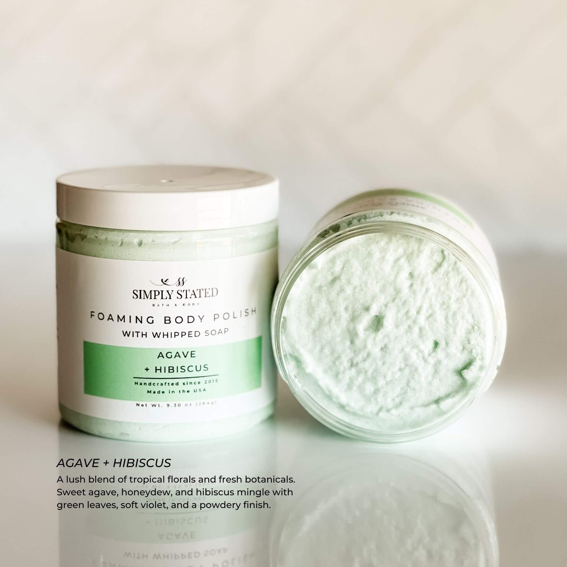 Simply Stated Foaming Body Polish in Agave + Hibiscus – light green whipped sugar scrub with a tropical floral scent and smooth, airy texture, shown in an open jar.
