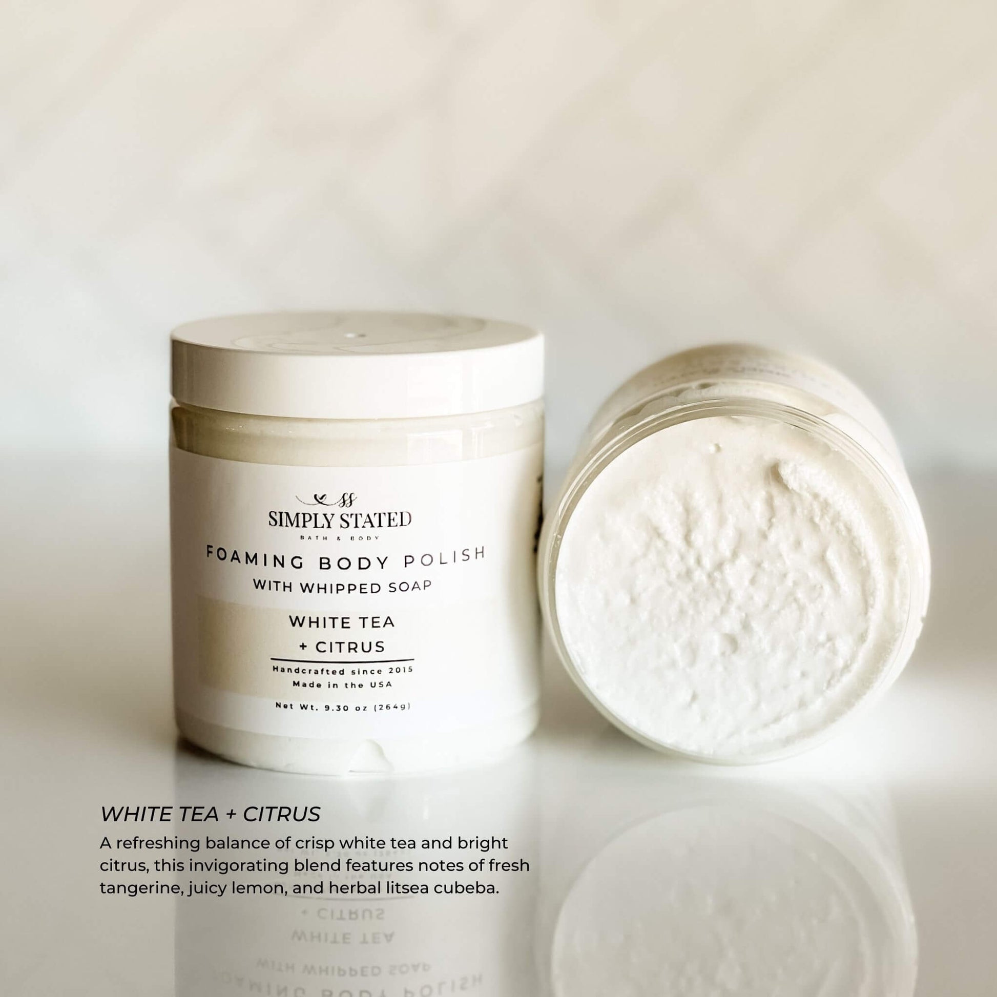 Simply Stated Foaming Body Polish in White Tea + Citrus – creamy white whipped scrub with invigorating citrus and herbal scent, styled with jar open and closed.