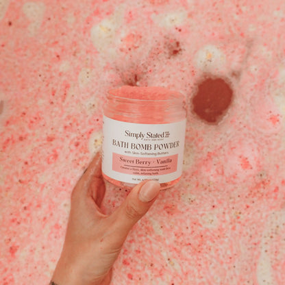 Sweet Berry + Vanilla Bath Bomb Powder jar held over pink bubble bath water