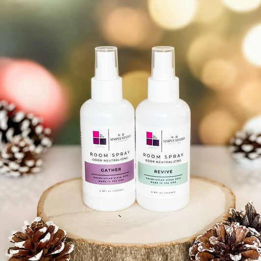 The Block x Simply Stated Room Sprays with odor neutralizing base featuring scents in Gather and Revive with a warm winter glow background and pinecone decorations.