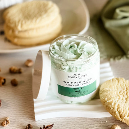 Simply Stated Frosted Noel Whipped Soap with mango butter, swirled mint-green lather beside sugar cookies and spices.
