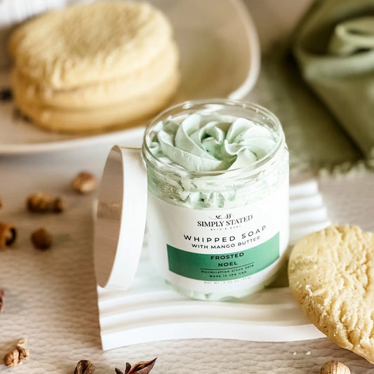 Simply Stated Frosted Noel Whipped Soap with mango butter, swirled mint-green lather beside sugar cookies and spices.