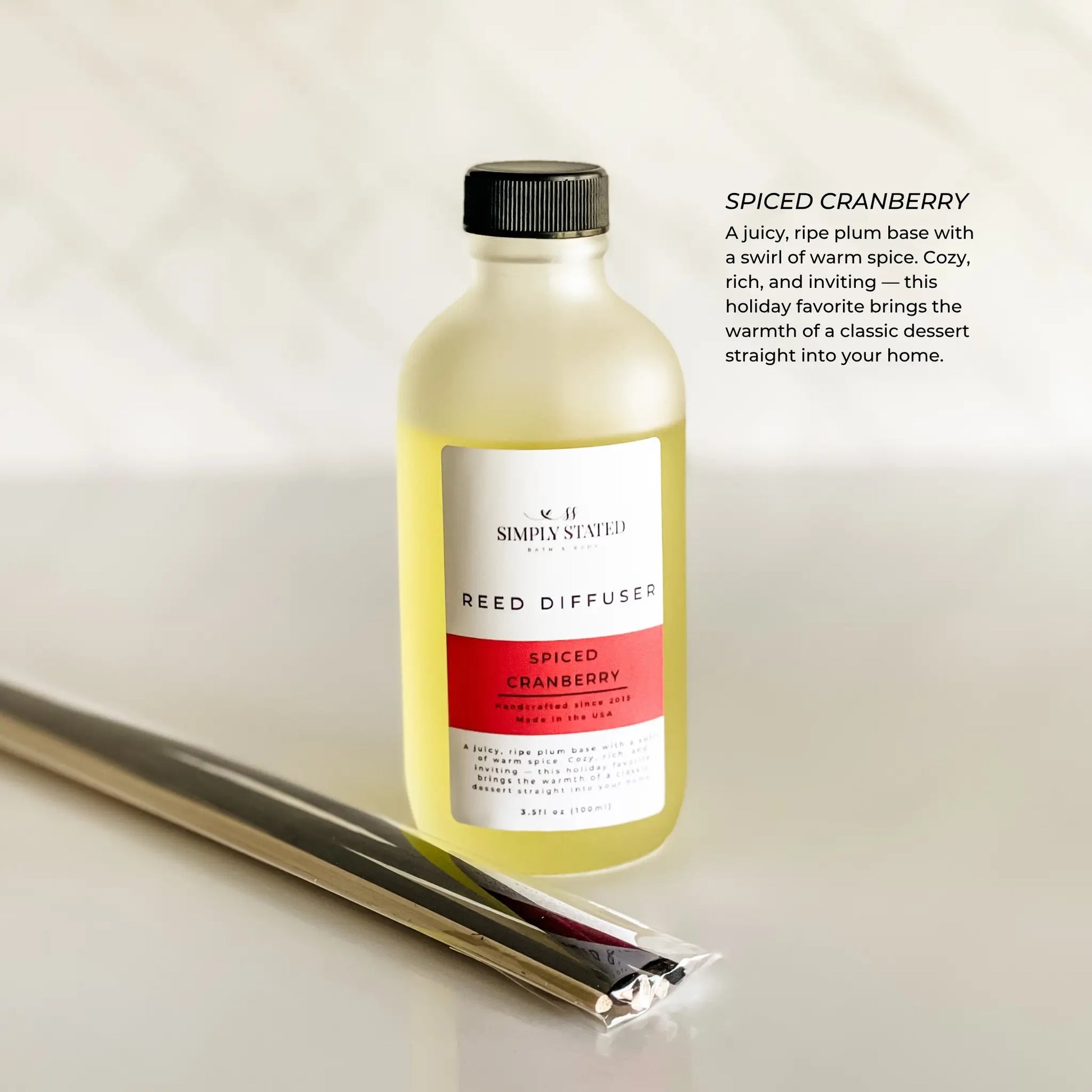 Reed diffuser bottle labeled 'Spiced Cranberry' on a light background