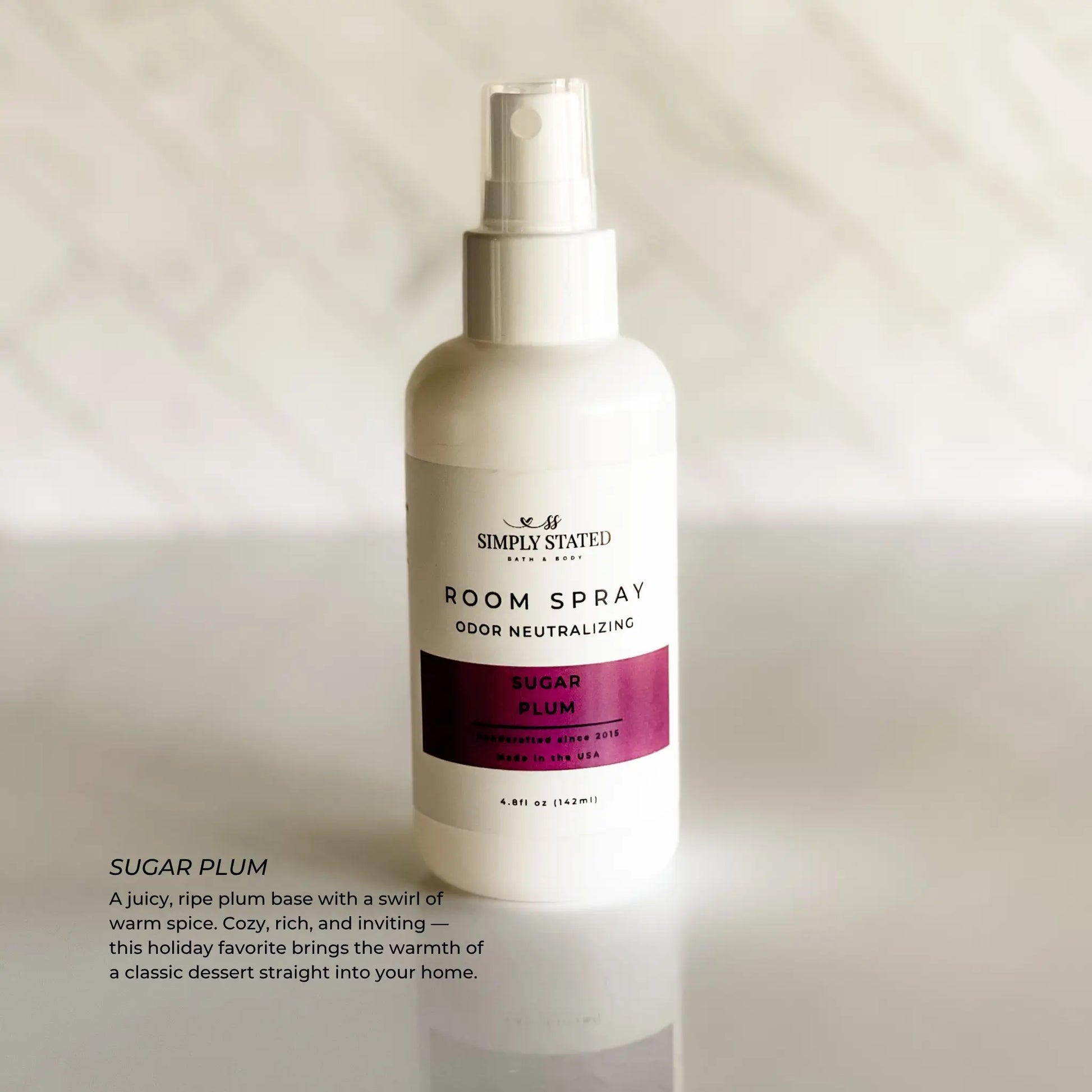 Room spray bottle labeled 'Simply Stated' with 'Sugar Plum' description on a neutral background