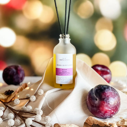 Reed diffuser with plums and berries on a decorative surface