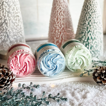Simply Stated Whipped Soap trio with mango butter, pink, blue, and green swirled lather among frosted trees.