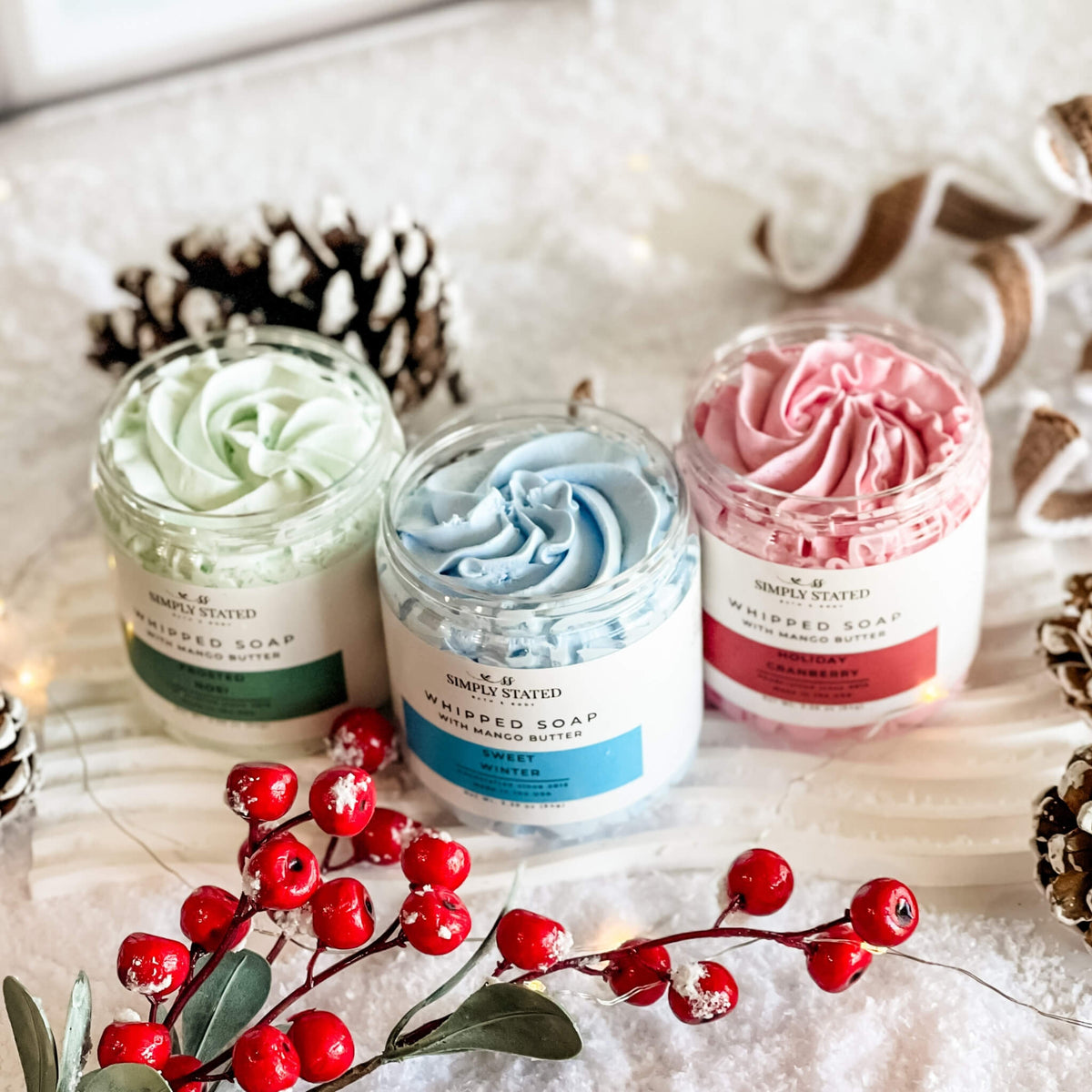 Simply Stated Whipped Soap trio with mango butter, green, blue, and pink lather in a snowy holiday scene.