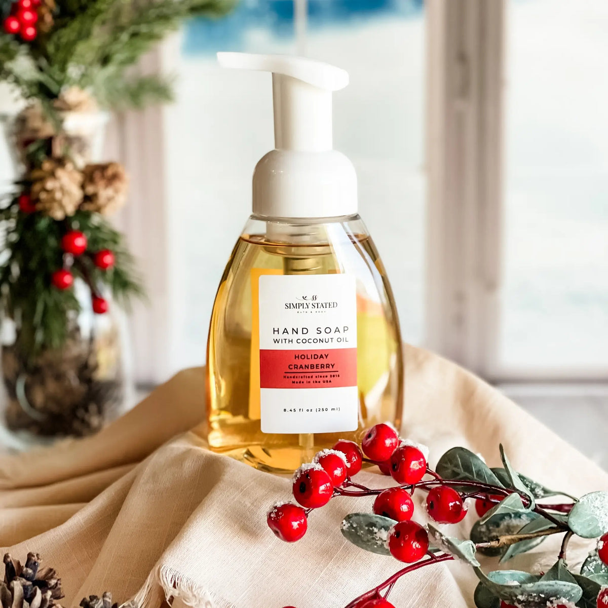 Simply Stated Holiday Cranberry Foaming Hand Soap with coconut oil, festive scene with red berries and pinecones.