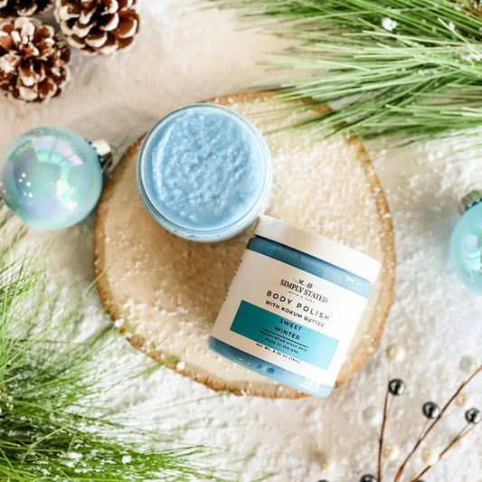 Simply Stated Sweet Winter Body Polish with kokum butter, blue sugar scrub styled with pine and pinecones.